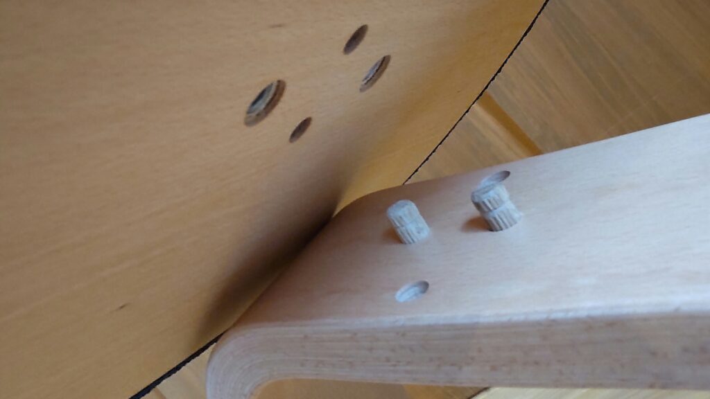 座面裏の穴に木製ピンを挿し込む様子